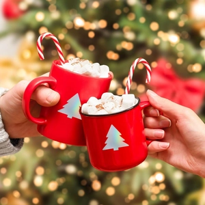 Close-up of festive red mugs with silver trees and candy canes in a cozy holiday setting
