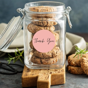 Pink round 'Thank You' stickers applied on a glass cookie jar for decorative gift sealing