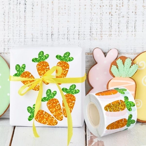 Close-up of glittery carrot stickers on white wood for Easter gift packaging seal