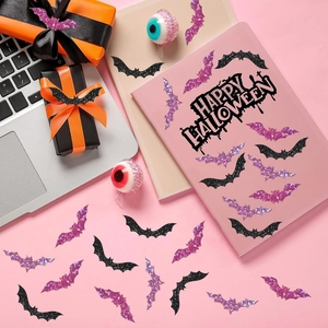 Close-up of glitter bat stickers and Halloween decorations on a pink office desk setup