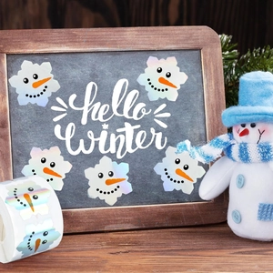 Close-up of holographic snowman stickers roll with Hello Winter holiday decoration