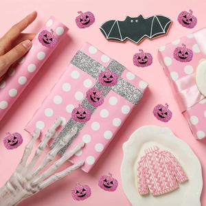 Close-up of pink glitter Halloween pumpkin stickers on festive gift packaging