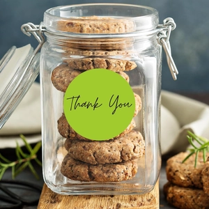 Detail of round green Thank You sticker on a glass jar containing handmade cookies