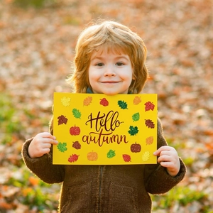 Close-up of glittery autumn stickers with maple leaf and pumpkin on yellow cardstock