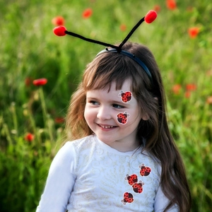 Close-up of holographic ladybug stickers and a matching headband on a young girl model