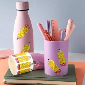 Close-up of glittery pencil-shaped decorative stickers on a cup and stationery set