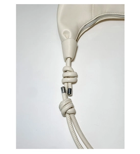 Detail of cream leather shoulder strap with minimalist knot and silver metal hardware