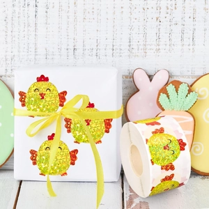 Glittery Easter chick sticker on white gift box with yellow ribbon for gift wrapping