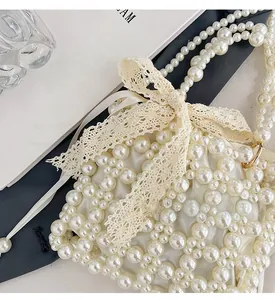 Detail of handmade pearl woven mini bag with lace bow and long pearl strap