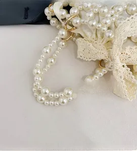 Detail of woven faux pearl handbag featuring golden ring hardware and lace bow accent