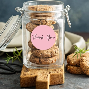 Detail of Thank You sticker on a glass jar with cookies on a rustic wood board