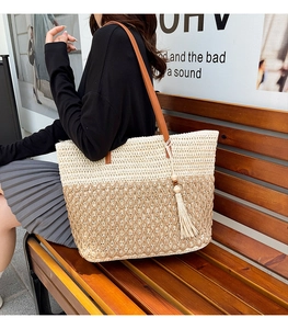 Detail of a large woven tote bag with contrast panels and brown leather handles