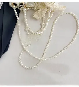 Detail of woven faux pearl shoulder strap with gold ring clasp on elegant lace handbag