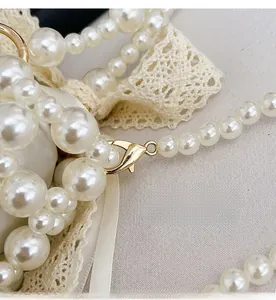 Close-up of pearl woven shoulder strap with durable gold metal lobster clasp