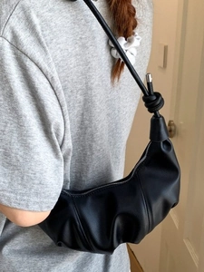 Black crescent-shaped underarm bag with pleated design and knotted shoulder strap