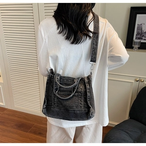 Detail of dark grey denim crossbody bag with adjustable strap and vintage texture