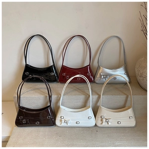 Collection of sleek bow shoulder bags in multiple colors shown on stone steps