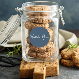 Close-up of a blue Thank You seal sticker on a glass storage jar with metal lid