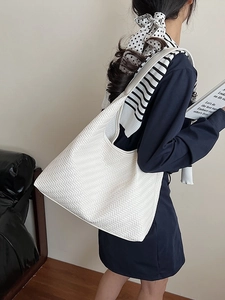 Minimalist white woven tote bag with herringbone texture shown in a stylish shoulder carry