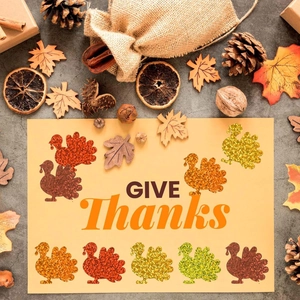 Macro shot of glitter turkey GIVE THANKS stickers with autumn maple leaves and pine cones