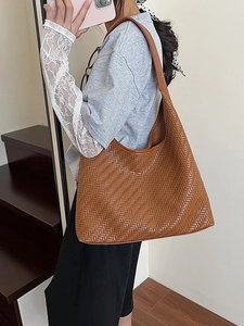 Brown woven leather tote bag with a minimalist design for women shown on a model