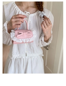 Dettaglio di una mini borsa rosa con pizzo e fiocco, tenuta da una modella