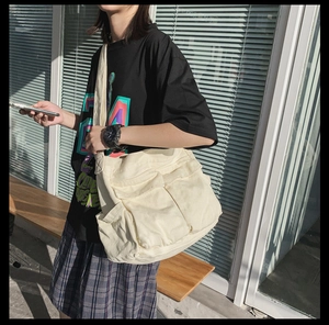 Detail view of large canvas messenger bag with double pockets on an outdoor model