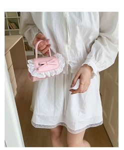 Dettaglio della mini borsa rosa con pizzo ricamato, fiocco decorativo e pelle PU