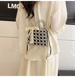 Detail of black beaded handbag with white lace bow and delicate metallic chain strap