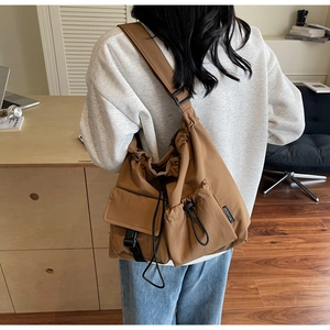 Detail view of khaki nylon crossbody bag showing tactical pockets and adjustable strap