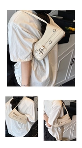 Detail showing creamy white patent leather underarm bag with decorative bow and silver buckles