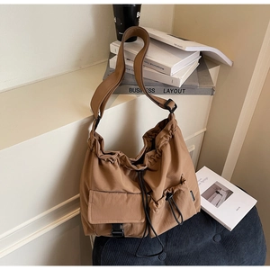 Detail of camel nylon messenger bag featuring drawstring closure and buckle pocket
