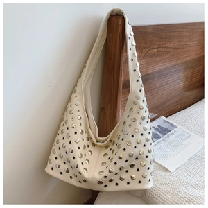 Détail du sac seau punk crème avec clous métalliques argentés accroché au lit