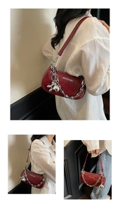 Detail of red textured underarm bag with silver chain and rabbit charm on model