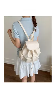 Rear view of model wearing a minimalist cream faux leather drawstring backpack for women