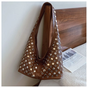 Détail d'un sac seau marron foncé orné de rivets argentés et d'une large bandoulière