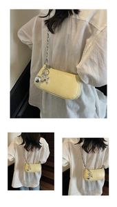 Detail of light yellow embossed leather bag with silver chain and balloon dog charm