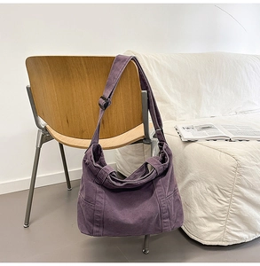 Detail of purple canvas tote bag with side pocket and adjustable buckle strap on a chair