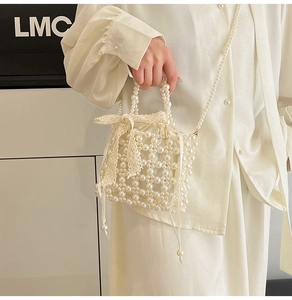Detail of hand-woven pearl bucket bag featuring lace bow and long pearl chain strap