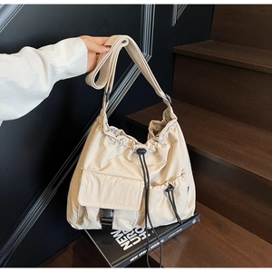 Detail of beige canvas tote bag showing drawstring pockets and black plastic buckle closure