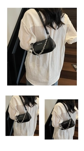 Close-up of black glossy crocodile pattern shoulder bag with silver chain and ball charm