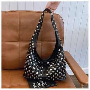 Détail d'un sac hobo punk noir avec clous ronds argentés et décorations d'œillets