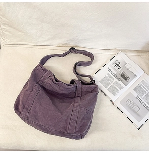 Close-up of a large purple canvas tote bag with wide strap on a soft fabric sofa