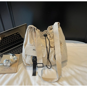 Detailed view of large-capacity beige canvas shoulder bag with functional drawstring detail