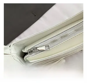 Macro detail of glossy white leather bag featuring a polished silver metal zipper closure