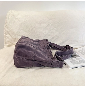Detail of a large purple canvas tote bag with stitched seams and wide strap on a soft surface