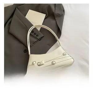 Detail of white patent leather shoulder bag with bow and silver metal buckle accents
