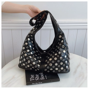 Détail du sac seau punk avec rivets ronds argentés et œillets sur cuir noir brillant