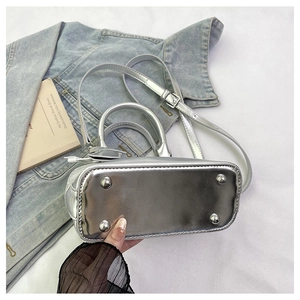 Detailed bottom view of silver shell bag showing four metallic protective base studs