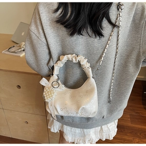 Détail d'un sac à main plissé blanc crème avec imprimé digital, perle et ruban élégant